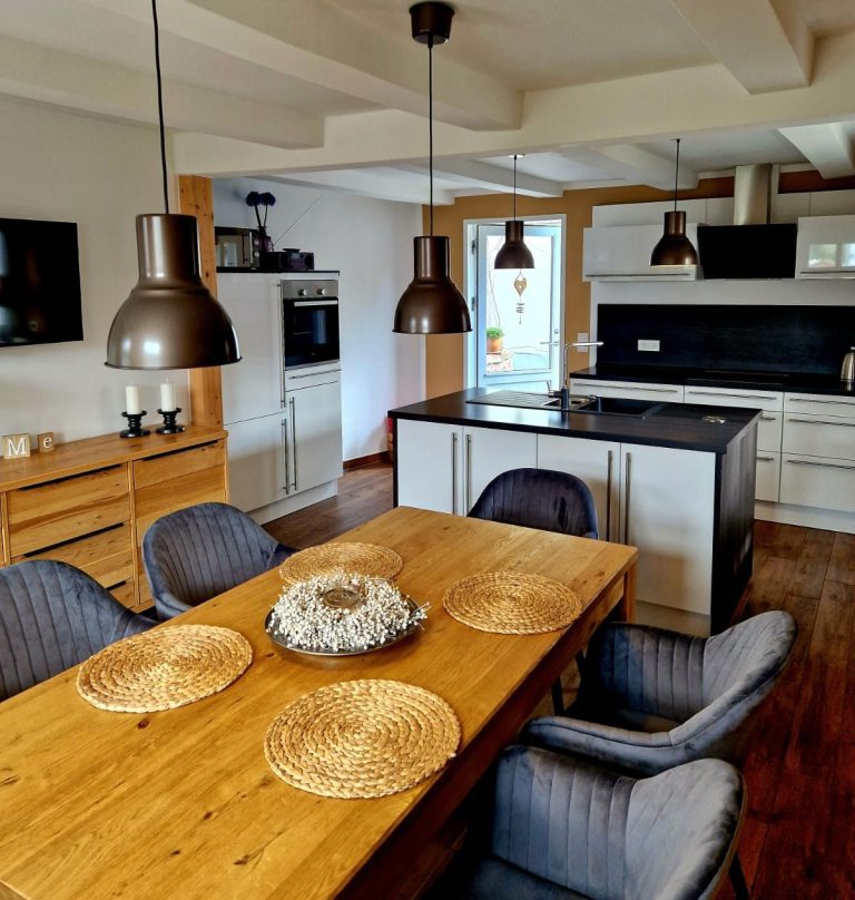 Küche Moderne Küche mit Holz-Essbereich, Pendelleuchten und großen Fenstern.